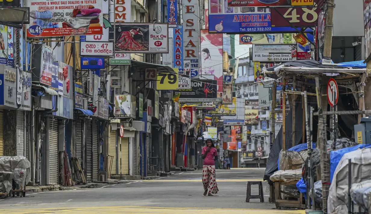 Seorang perempuan melintas di sepanjang jalan yang sepi setelah pemerintah memberlakukan pembatasan perjalanan dan lockdown akhir pekan di Kolombo, Sri Lanka, Sabtu (22/5/2021). Sri Lanka pada Jumat, 21 Mei mencatat 3.547 kasus harian corona Covid-19. (Ishara S. KODIKARA/AFP)