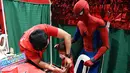 Seorang anak menerima vaksin Covid-19 Pfizer-BioNtech untuk anak-anak berusia 5-11 tahun saat seseorang berkostum superhero Spider-Man terlihat di gym di San Juan City, pinggiran kota Manila, Filipina pada 7 Februari 2022. (Ted ALJIBE / AFP)