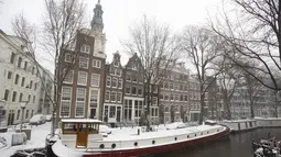 Salju menutupi rumah perahu di Amsterdam, karena salju dan angin kencang menyelimuti sebagian besar Belanda, Minggu (7/2/2021). Peringatan bahaya cuaca ekstrem telah dikeluarkan oleh pihak BMKG Belanda. (AP Photo/Peter Dejong)