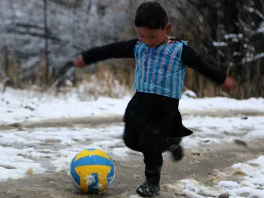 Seorang anak laki-laki Afghanistan, Murtaza Ahmadi berkaos kantong kresek timnas Argentina milik Lionel Messi terlihat bermain bola di  kabupaten Jaghori, provinsi Ghazni, 29 Januari 2016. Sebelumnya, foto Murtaza itu menyebar luas di dunia maya (STR/AFP)
