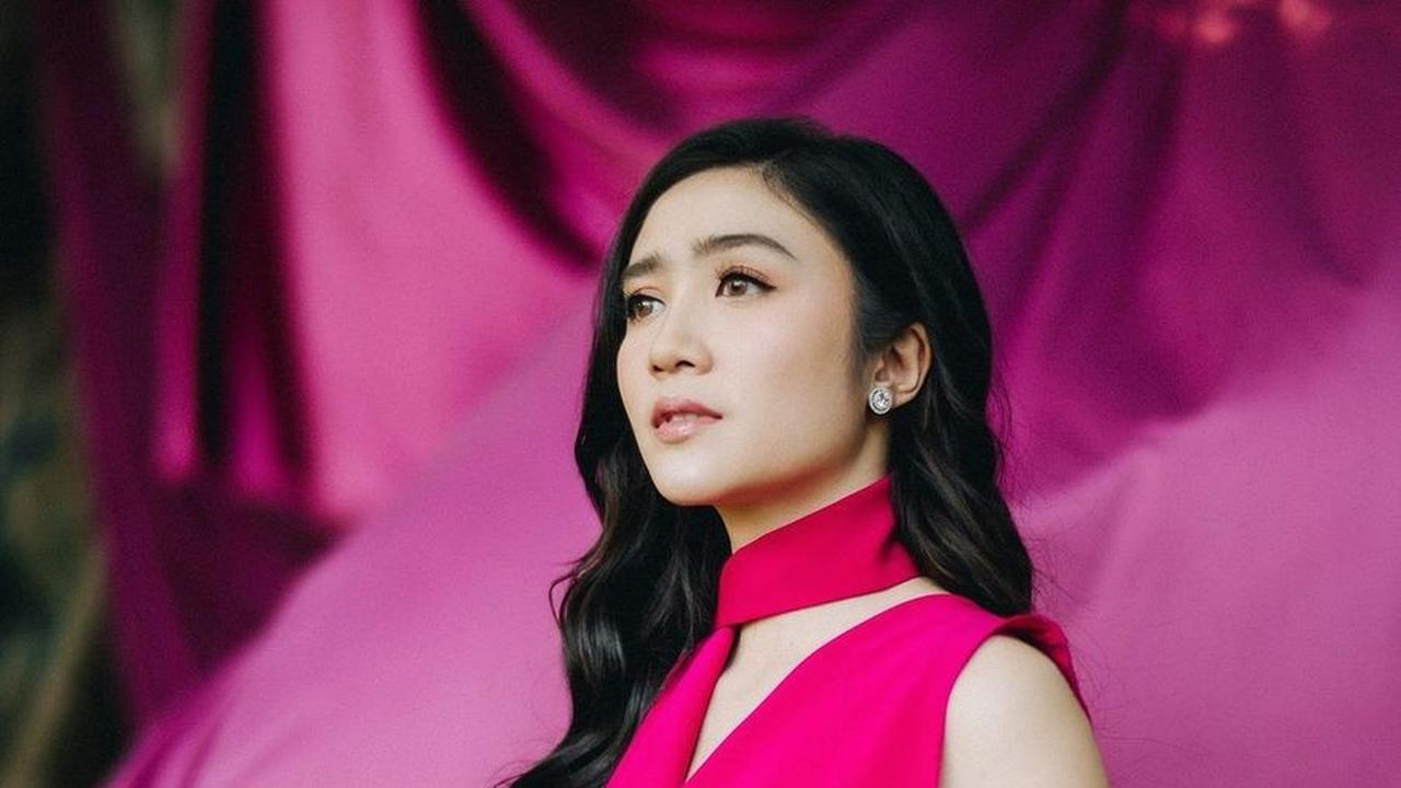 Febby tampil menawan dalam dress pink cerah karya Pamela Usanto, dipadukan dengan bunga senada dan latar belakang pink magenta yang mencolok.<br><br>