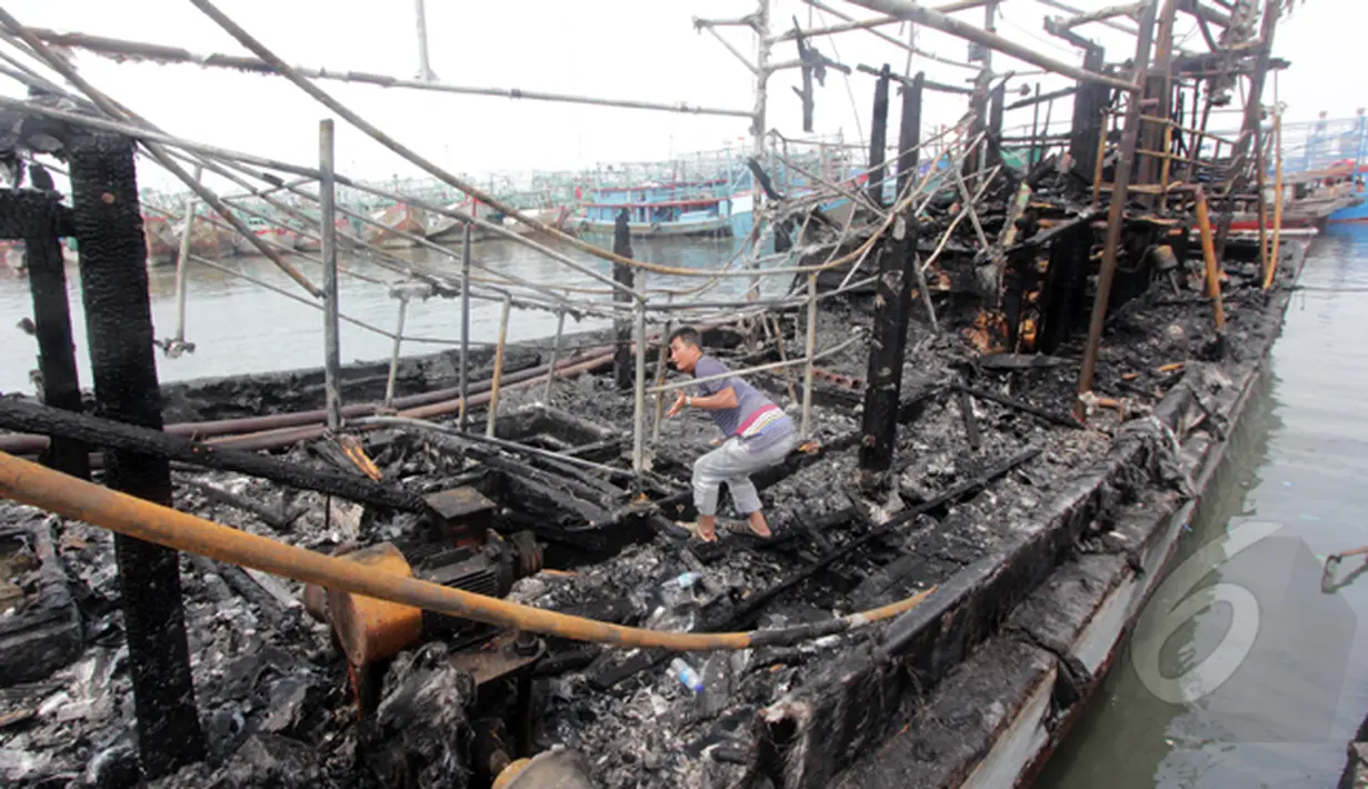 Seorang lelaki memasuki area kapal yang terbakar di Pelabuhan Muara Angke, Jakarta, Jumat (27/2/2015). Diduga kebakaran disebabkan korsleting listrik. Kerugian ditaksir mencapai ratusan juta. (Liputan6.com/Johan Tallo)