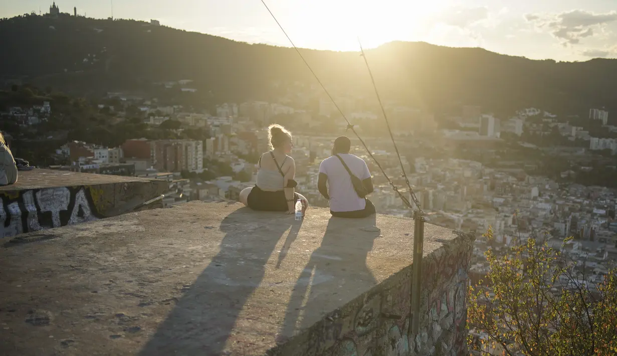 Orang-orang duduk di sudut pandang panorama kota Barcelona, Spanyol, Senin (21/10/2021). Barcelona adalah sebuah kota terbesar kedua di Spanyol dan merupakan ibu kota wilayah otonom Katalonia. (AP Photo/Joan Mateu)
