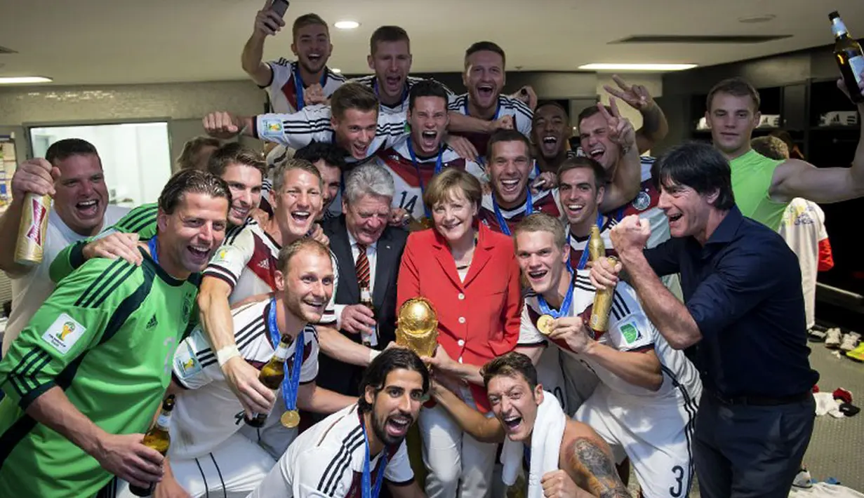 Kanselir Jerman, Angela Merkel (tengah), saat merayakan gelar juara dunia 2014 bersama para pemain di ruang ganti di Stadion Maracana, Rio de Janeiro, Brasil, (13/7/2014). (AFP PHOTO/Bundesregierung/Guido Bergmann) 