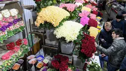 Pedagang bunga melayani pembeli jelang Hari Perempuan Internasional di pasar bunga di Moskow, Rusia (5/3). Hari Perempuan Internasional secara resmi dijadikan sebagai hari libur nasional di Soviet Rusia pada tahun 1917. (AFP Photo/Kirill Kudryavtsev)