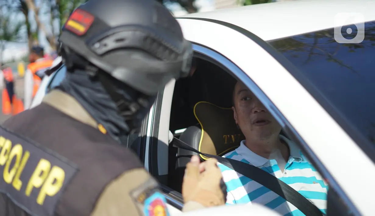 Petugas Satpol PP berbicara dengan pengemudi mobil saat operasi kepatuhan disiplin masker di kawasan Waduk Sunter, Jakarta, Selasa (8/9/2020). Warga yang kedapatan melanggar akan dikenakan sanksi denda Rp 250 ribu atau membersihkan fasilitas umum. (Liputan6.com/Immanuel Antonius)
