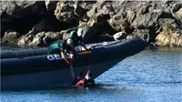 Penjaga Sipil Spanyol menarik seorang pria yang berhasil berenang ke Ceuta masuk ke perahu karet. (AFP/Antonio Sempere).