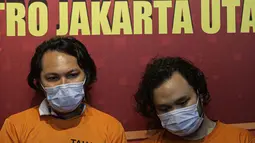 Vokalis grup band Deadsquad Daniel Mardhany (kiri) dan rekannya saat rilis kasus narkoba di Polres Jakarta Utara, Senin (3/5/2021). Kapolres Metro Jakarta Utara Kombes Pol Guruh Arif Darmawan mengatakan dalam penangkapan diamankan tembakau sintetis serta obat prohiper. (Liputan6.com/Faizal Fanani)