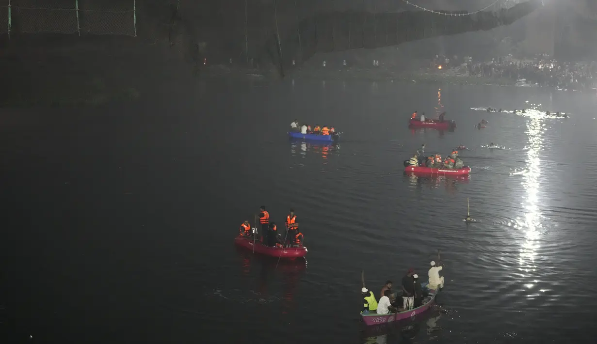 Tim penyelamat di kapal mencari di sungai Machchu di sebelah jembatan kabel yang runtuh di kota Morbi di negara bagian barat Gujarat, India, Senin, 31 Oktober 2022. Sedikitnya 81 orang tewas akibat kejadian tersebut. (AP/Ajit Solanki)