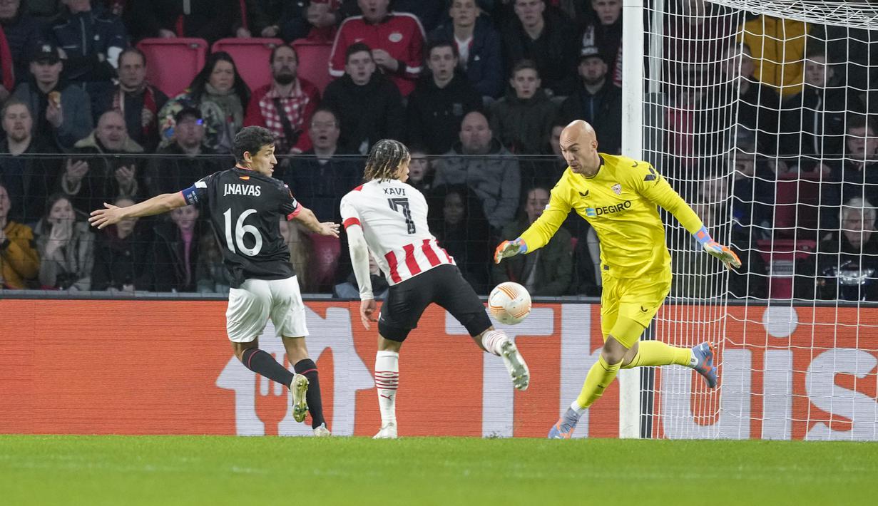 <p>Kiper Sevilla, Marko Dmitrovic berhasil mengamankan bola dari ancaman pemain PSV, Xavi Simons dalam laga leg kedua babak playoff fase gugur Liga Europa 2022/2023 di Philips Stadium, Eindhoven, Jumat (24/2/2023). (AP Photo/Peter Dejong)</p>