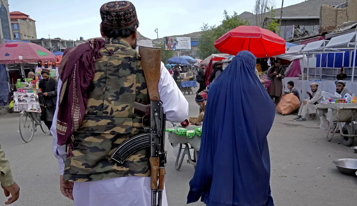 <p>Seorang perempuan mengenakan burqa berjalan melalui pasar lama ketika Taliban berjaga-jaga, di pusat kota Kabul, Afghanistan, 8 Mei 2022. Taliban memerintahkan perempuan Afghanistan untuk mengenakan pakaian dari kepala hingga ujung kaki atau burqa tradisional di depan umum. (AP Photo/Ebrahim Noroozi)</p>