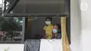 Pasien Covid-19 bersama seorang anak terlihat dari jendela Graha Wisata Ragunan, Jakarta, Selasa (15/6/2021). Pemprov DKI memfungsikan kembali Graha Wisata Ragunan sebagai tempat isolasi warga terpapar COVID-19 kategori OTG sejak pekan lalu dan saat ini merawat 117 pasien. (merdeka.com/Arie Basuki)