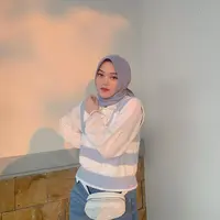 Begini potret adik Rizky Febian memadukan kemeja dengan vest dan celana jeans. Hijab segi empat yang ia kenakan memperlihatkan pipinya yang semakin tirus. (Instagram/putridelinaa).