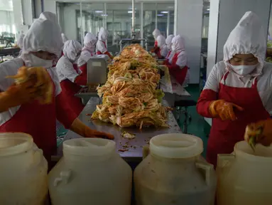 Dalam foto pada 1 Desember 2020, pekerja menyortir kubis di lini produksi pembuatan kimchi di Pabrik Kimchi Ryugyong di Pyongyang, Korea Utara. Setiap tahunnya, pabrik itu menghasilkan sekitar 4.200 ton acar khas Korea yang terbuat dari sayuran kubis yang diawetkan tersebut. (KIM Won Jin/AFP)