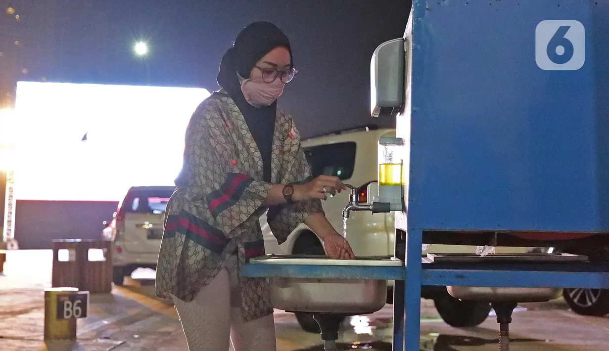 Penonton mencuci tangan saat menyaksikan pemutaran film secara drive-in di Cikarang, Bekasi, Jawa Barat, Rabu (3/6/2020). Kehadiran drive-in cinema memberikan hiburan alternatif kepada warga di tengah pandemi virus corona COVID-19. (Liputan6.com/Herman Zakharia)