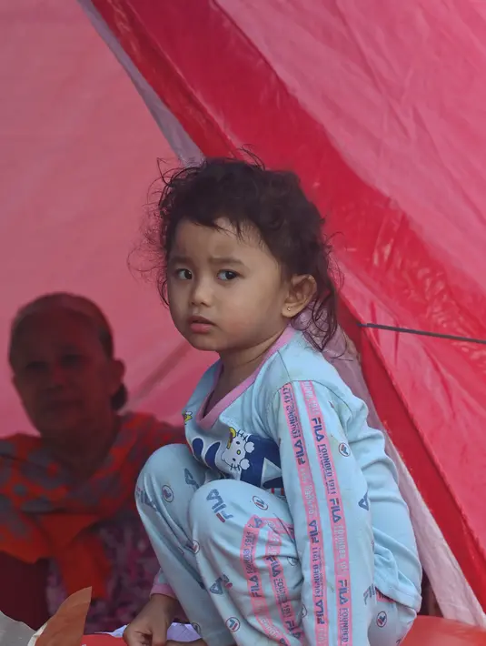 Seorang gadis sedang sarapan di kamp sementara setelah gempa berkekuatan 6,2 di Mamuju,  Senin (18/1/2021). Pengungsi masih mengharapkan bantuan berupa bahan pangan dan obat-obatan karena rata-rata para pengungsi merupakan anak-anak, yang rawan terserang penyakit. (AFP/Adek Berry)
