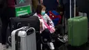Seorang anak mengenakan masker duduk di antara koper-koper di Bandara Internasional Hong Kong di Hong Kong, Selasa (21/1/2020). Masker terjual habis dan pemeriksaan suhu di bandara dan stasiun kereta api menjadi norma baru di China menyusul merebaknya wabah virus corona.  (AP/Ng Han Guan)