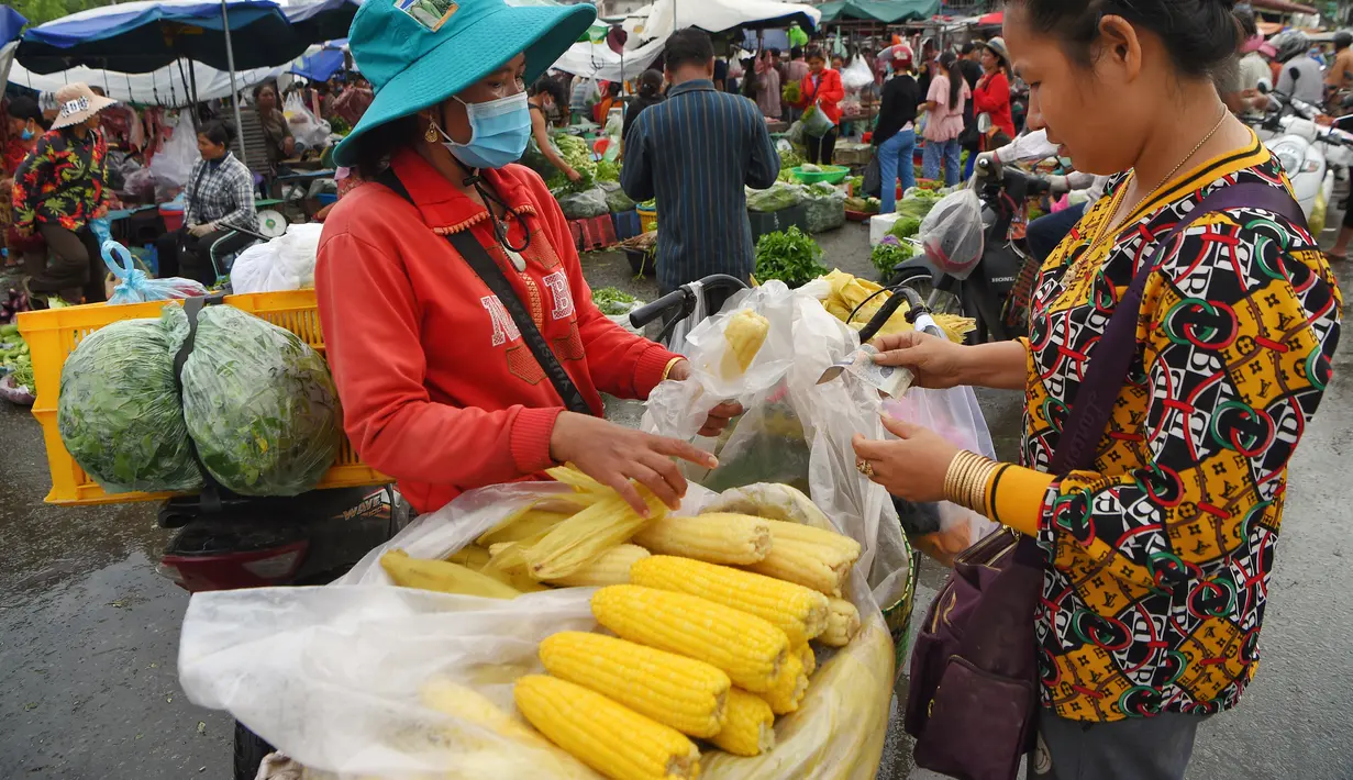 Seorang wanita membeli jagung rebus di sebuah pasar di Phnom Penh (24/7/2020). Pasar membentuk bagian integral dalam kehidupan orang Kamboja, dengan kunjungan harian yang dilakukan untuk persediaan makanan untuk hari itu serta barang-barang lainnya. (AFP/Tang Chhin Sothy)