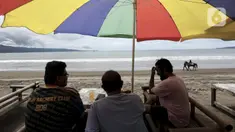 Warga bersantai di Pantai Pelabuhan Ratu, Kabupaten Sukabumi, Jawa Barat, Jumat (12/11/2021). Penerapan Pemberlakuan Pembatasan Kegiatan Masyarakat (PPKM) Level 1 membolehkan objek wisata kembali buka, salah satunya Pantai Pelabuhan Ratu. (Liputan6.com/Johan Tallo)