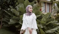 Perpaduan celana kulot dengan atasan blouse lengan lonceng warna putih bikin tampilan kondangan kian memesona. Tambahkan pula hijab pashmina warna lebih gelap dan heels. (Instagram/emyaghnia).