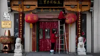 Seorang pekerja yang mengenakan masker membersihkan lentera berdebu di luar restoran di distrik perbelanjaan Wangfujing, Beijing, China, Rabu (14/12/2022). Mulai hari ini, Komisi Kesehatan Nasional China melaporkan penurunan kasus harian COVID-19 sejak pemerintah melonggarkan pengujian PCR setelah kasus harian mencapai rekor tertinggi. (AP Photo/Andy Wong)