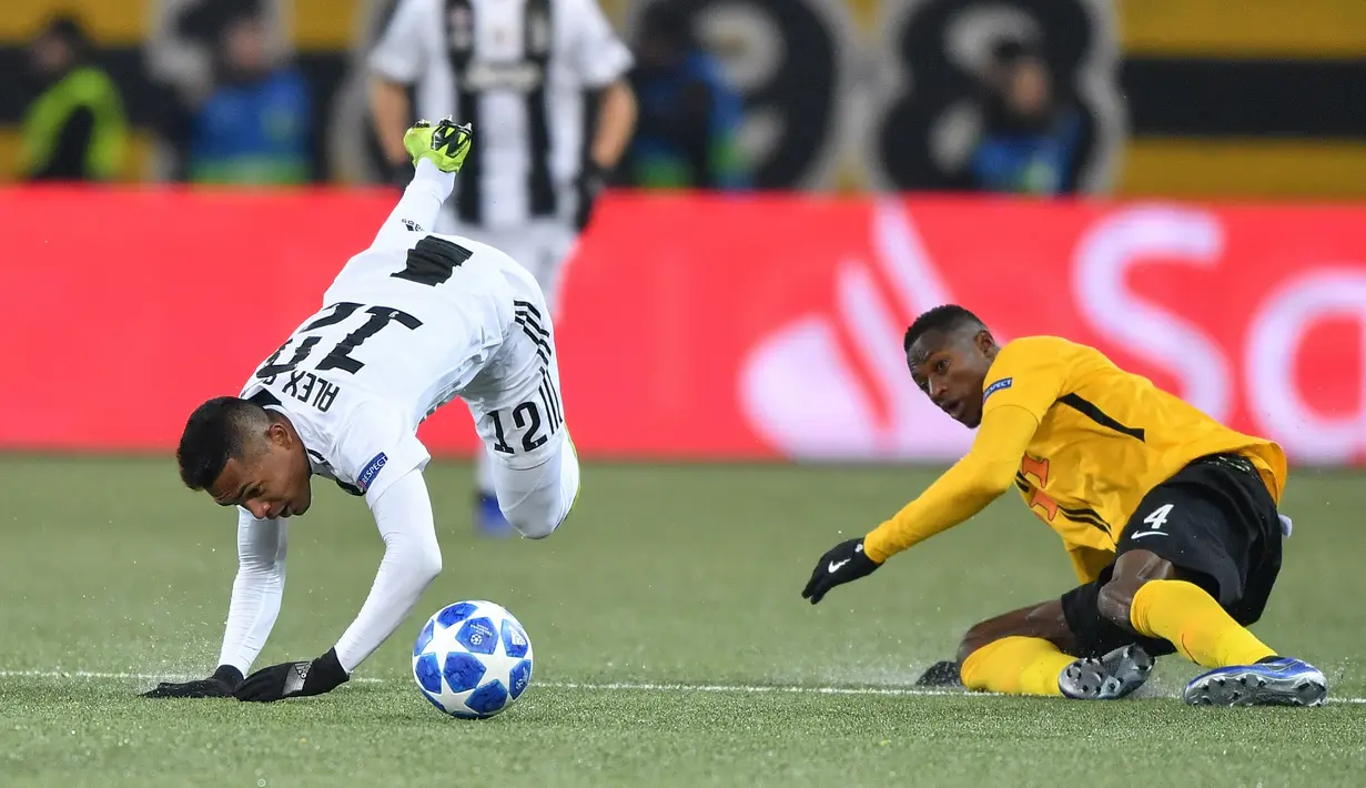Bek Juventus, Alex Sandro dan pemain Young Boys, Mohamed Ali Camara terjatuh saat berebut bola pada laga pamungkas Grup H Liga Champions di Stade de Suisse, Kamis (13/12). Juventus kalah 1-2 dari tuan rumah, Young Boys. (Fabrice COFFRINI/AFP)