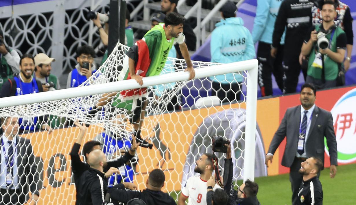 Pemain Yordania, Yazan Al-Naimat menaiki gawang saat merayakan kemenangan timnya atas Korea Selatan setelah laga semifnial Piala Asia 2023 di Ahmad Bin Ali Stadium, Doha, Qatar, Selasa (06/02/2024). (AP Photo/Hussein Sayed)