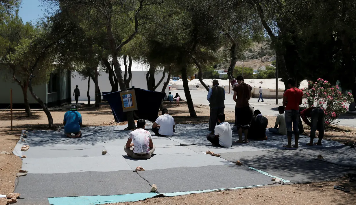 Sejumlah imigran khusyuk melaksanakan salat pada hari pertama Ramadan, di sebuah kamp pengungsian milik pemerintah Yunani di Schisto, Athena, Senin (6/6). Para imigran itu membuat masjid darurat di sebuah halaman terbuka. (REUTERS/Alkis Konstantinidis)