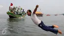 Seorang nelayan menceburkan diri ke laut saat mengikuti sedekah bumi Nadran di Muara Angke, Jakarta, Minggu (13/12). Tradisi ini sebagai ungkapan rasa syukur kepada Tuhan YME atas hasil laut yang diperoleh. (Liputan6.com/Helmi Afandi)
