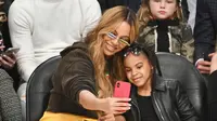 Penyanyi Beyonce dan putrinya Blue Ivy Carter berselfie saat menonton pertandingan NBA All-Star Game 2018 di Staples Center di Los Angeles, California, AS (18/2). (Allen Berezovsky/Getty Images/AFP)