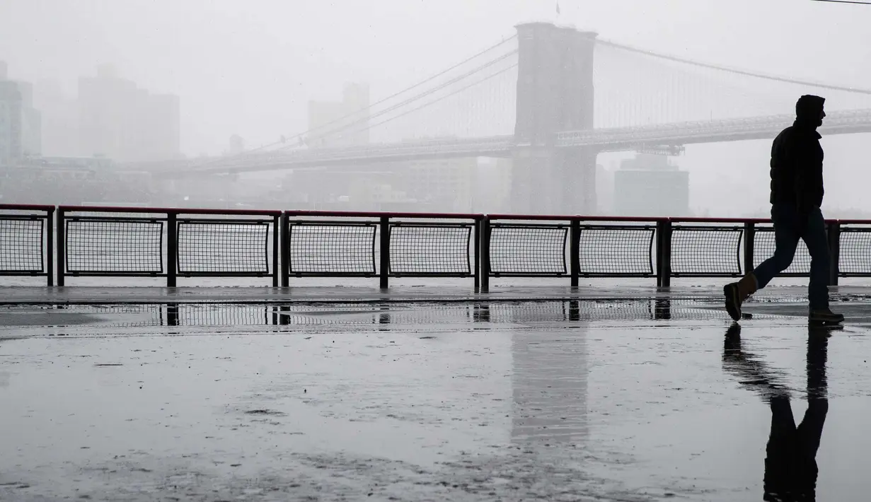 Seorang pejalan kaki melintas di dekat jembatan Manhattan saat badai salju di bawah drive Franklin Delano Roosevelt di New York (21/3). Badai salju yang melanda sebagian Amerika Serikat telah membawa salju dan angin kencang. (AP Photo / Mary Altaffer)