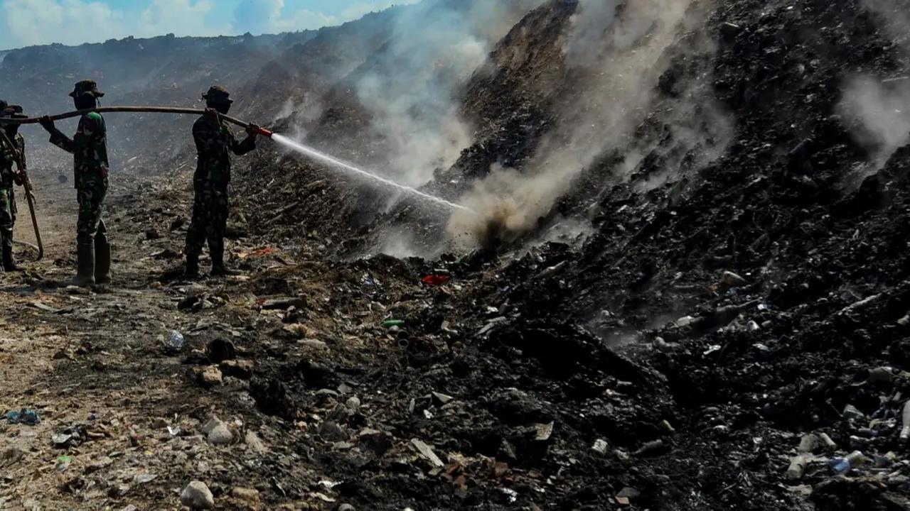 Dengan dibantu sejumlah rekannya, prajurit TNI AD menggunakan selang menyemprotkan air saat memadamkan titik-titik api di TPA Regional Sarbagita Suwung, Denpasar, Bali.