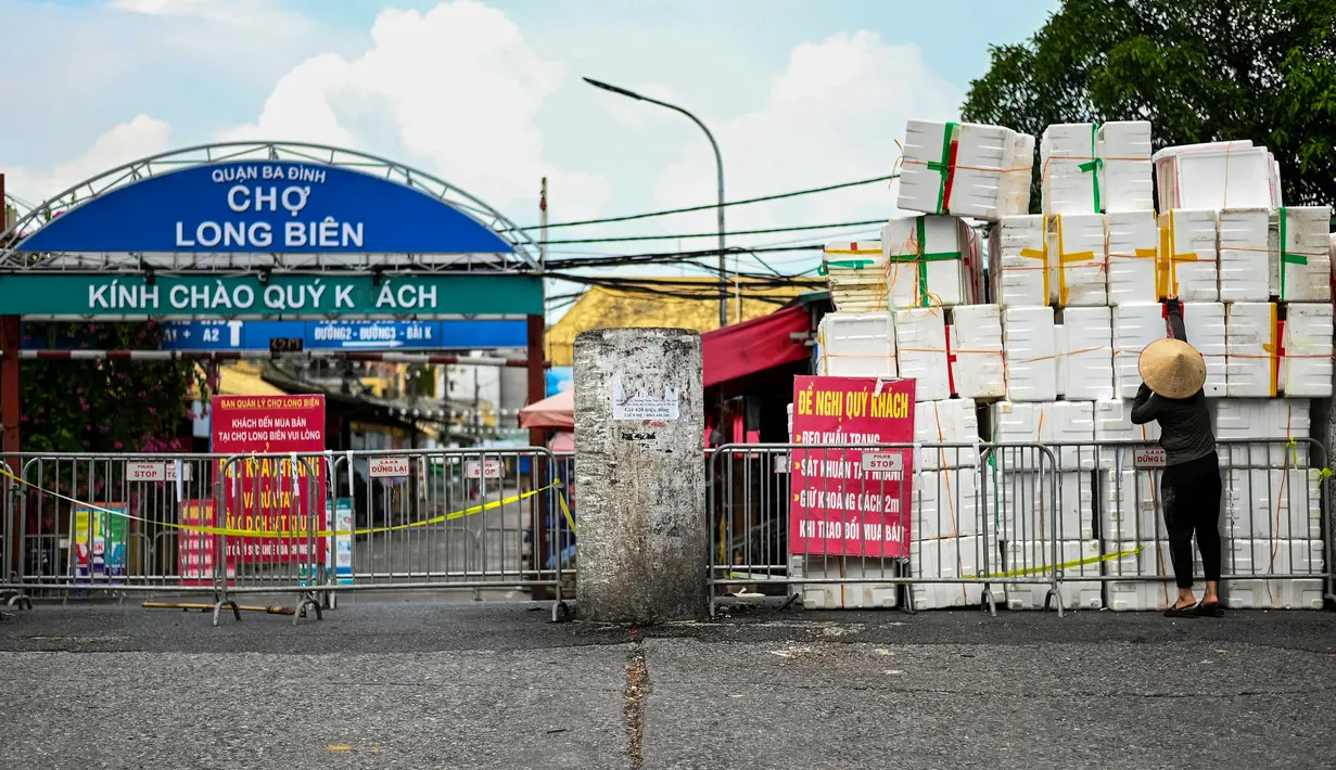 Seorang wanita mendorong kotak styrofoam kosong untuk membuat barikade improvisasi untuk membatasi pergerakan warga di Hanoi, Vietnam pada 30 Agustus 2021. Tiang bambu, peti bir, tangga dan kursi rusak: benda sehari-hari membentuk barikade sementara saat lockdown Covid-19. (Manan VATSYAYANA/AFP)