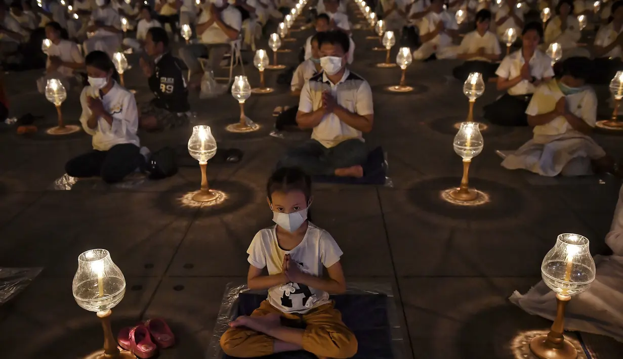 Umat Buddha mengenakan masker saat berdoa bersama di kuil Buddha Wat Dhammakaya, Bangkok (31/1/2020). Pemerintah Thailand mengumumkan 14 orang terkonfirmasi infeksi virus corona.Thailand memiliki jumlah kasus terbesar kedua di luar China. (AFP Photo/Lillian Suwanrumpha)
