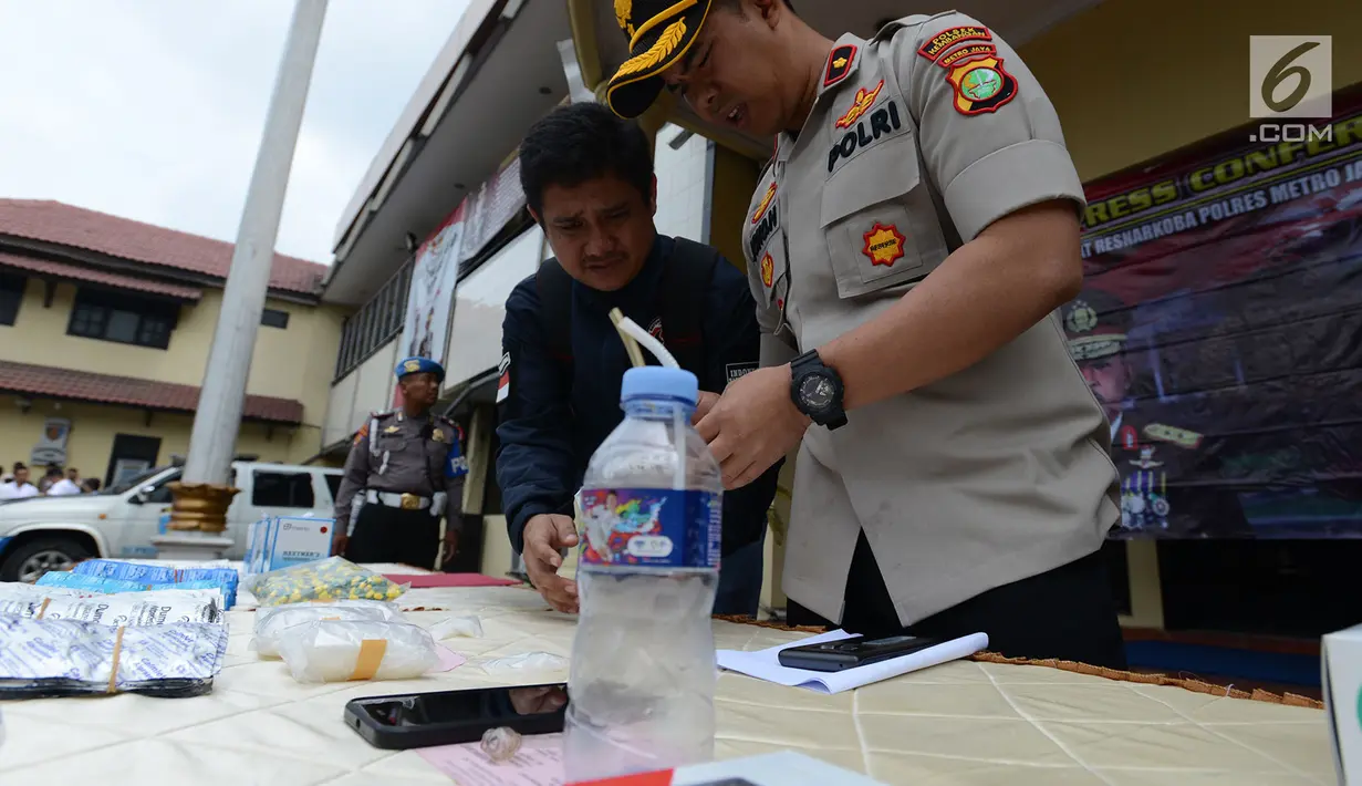 Petugas mengecek barang bukti narkoba saat menggelar perkara kasus pengedaran narkoba jenis shabu dan psikotopika golongan IV serta obat daftar G pada sebuah sekolah di Jakarta, Selasa (15/1). (Merdeka.com/Imam Buhori)