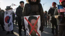 Pengunjuk rasa anti-Korea Utara membawa poster Kim Jong-Un saat menggelar aksi di pelabuhan Mukho di Donghae, Korea Selatan (6/2). (AFP/Ed Jones)