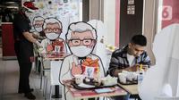 Pelayan merapikan banner bergambar karakter di KFC Salemba, Jakarta, Selasa (23/6/2020). Banner bergambar tersebut berguna untuk pembatas bagi pengunjung yang makan di tempat saat fase kenormalan baru. (Liputan6.com/Faizal Fanani)