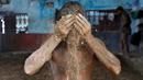 Seorang pegulat menaburkan lumpur ketubuhnya agar tidak terjatuh karena berkeringat saat berlatih di pusat pelatihan tradisional di tepi Sungai Gangga menjelang Bengal kejuaraan gulat lumpur, di Kolkata, India 17 Mei 2016. (REUTERS/Rupak De Chowdhuri)