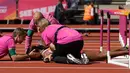 Petugas medis memberikan pertolongan kepada atlet Trinidad dan Tobago, Deborah John yang cedera usai terjatuh dalam cabang lari halang rintang 100 meter putri Kejuaraan Atletik Dunia di Stadion London, Inggris (11/8). (AP Photo/Matt Dunham)