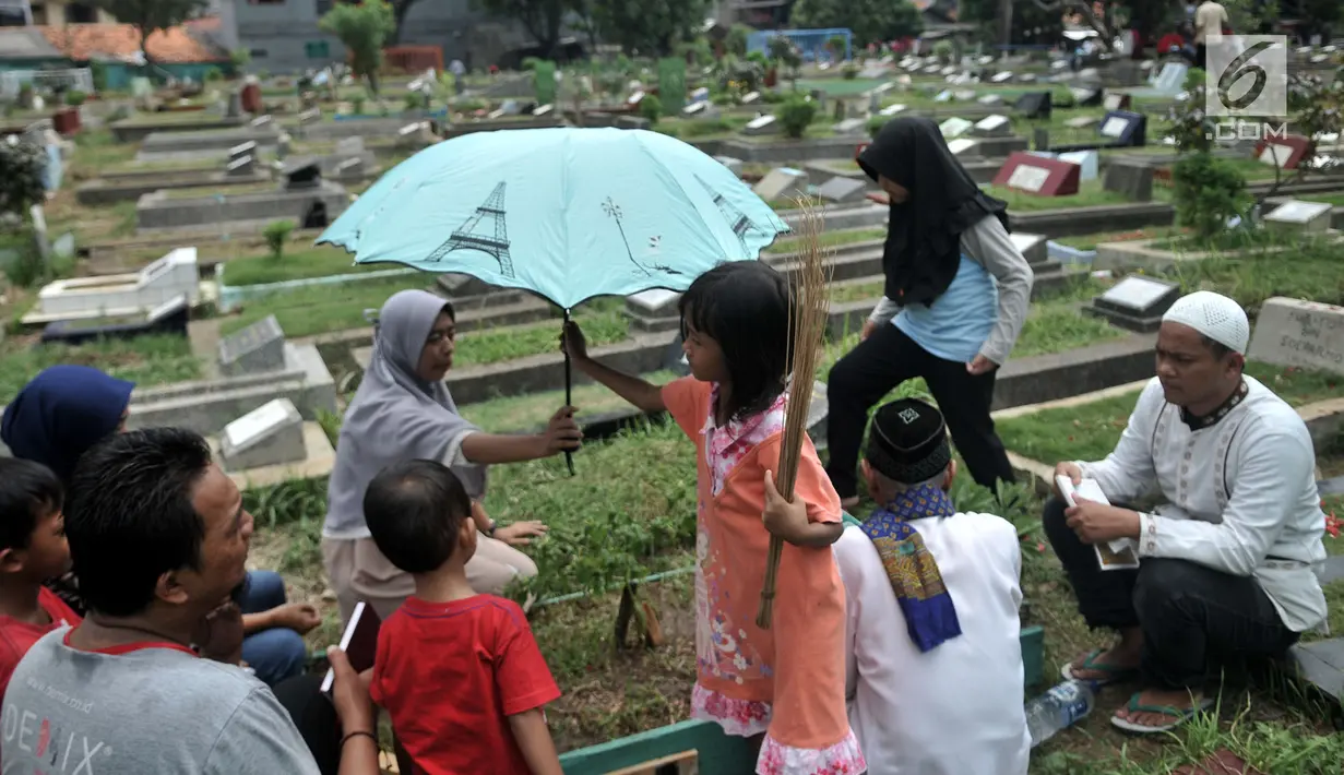 Seorang anak saat memayungkan peziarah di salah satu makam di TPU Cipinang Baru, Jakarta, Minggu (5/5). Jasa Ngoret ini dilakukan atas keinginan anak-anak tersebut bukan karena paksaan dan sebagian mereka menyisihkan hasilnya untuk membantu orang tua. (merdeka.com/Iqbal S. Nugroho)