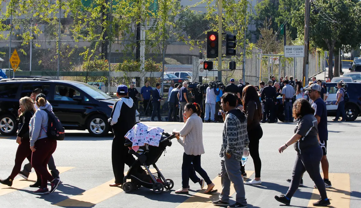 Para wali murid menunggu anak mereka di seberang lokasi penembakan di sekolah menengah Salvador Castro, Los Angeles, Kamis (1/2). Kepolisian mengatakan bahwa tersangka penembak dan senjata yang dimiliki sudah diamankan oleh polisi. (AP/Damian Dovarganes)