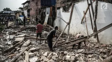 Warga mengumpulkan besi dari puing-puing sisa penertiban bangunan di bantaran Sungai Ciliwung, kawasan Bukit Duri, Jakarta Selatan, Selasa (11/7). Terdapat 355 bangunan yang ditertibkan guna menanggulangi banjir di Jakarta ini (Liputan6.com/Faizal Fanani)