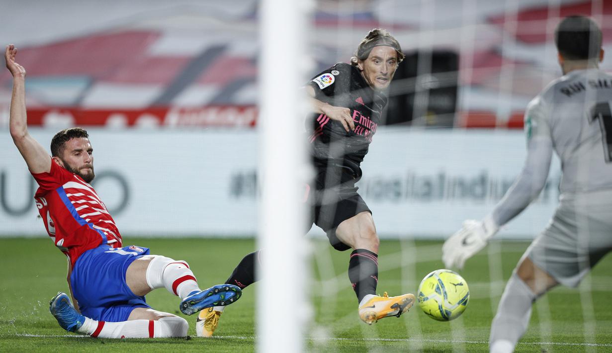 Gelandang Real Madrid, Luka Modric (tengah) melepaskan tendangan yang berbuah gol pertama timnya ke gawang Granada dalam laga lanjutan Liga Spanyol 2020/2021 pekan ke-36 di Los Carmenes Stadium, Granada, Kamis (13/5/2021). Real Madrid menang 4-1 atas Granada. (AP/Fermin Rodriguez)