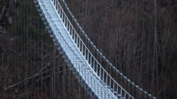 Foto yang diambil pada 3 Maret 2023 menunjukkan jembatan gantung yang sedang dibangun, menghadap ke air terjun di Todtnau, barat daya Jerman. Pembangunan jembatan sepanjang 450 meter yang digantung dengan ketinggian hingga 120 meter ini diharapkan selesai pada Mei 2023 dan menjadi daya tarik wisata utama di Black Forest. (PATRICK HERTZOG / AFP)