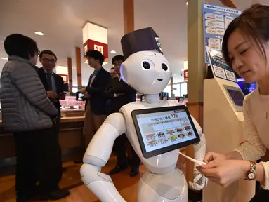 Seorang karyawati dari restoran sushi Hamazushi menguji coba robot humaoid Pepper saat press preview di Saitama, Jepang (2/2). Robot tersebut merupakan buatan dari perusahaan telekomunikasi raksasa Jepang yang bernama Softbank. (AFP/Kazuhiro Nogi)