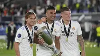 Gelandang Real Madrid, Luka Modric, Toni Kroos dan Casemiro berpose denga trofi usai pertandingan melawan Eintracht Frankfurt pada final Piala Super Eropa di Stadion Olimpiade Helsinki, Finlandia, Kamis (11/8/2022). Real Madrid menang atas Eintracht Frankfurt 2-0. (AP Photo/Antonio Calanni)