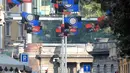 Warga melintas di bawah bendera klub Inter Milan dan AC Milan yang tergantung di jalan Paolo Sarpi, sebuah lingkungan China di Milan, Italia (13/10). Saat ini kedua tim tersebut merupakan milik pengusaha asal China. (AFP Photo/Miguel Medina)
