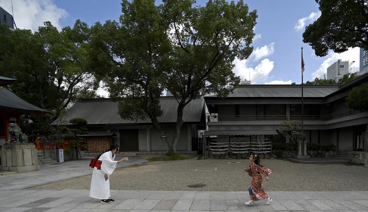 Seorang wanita memfoto anaknya saat mengunjungi Kuil Ikuta terlihat di pusat Kobe (5/10/2019). Kuil, dengan sejarah lebih dari 1.800 tahun ini dikatakan sebagai salah satu kuil tertua di Jepang. (AFP Photo/Monteforte)