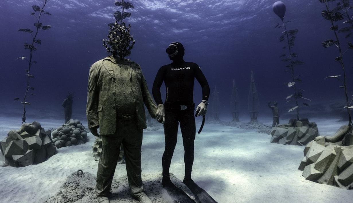 Penyelam bebas Angels Savvas berpose dengan patung di taman patung bawah laut MUSAM, Ayia Napa, Siprus, 18 September 2021. MUSAM disebut sebagai hutan bawah laut pertama di dunia. (EMILY IRVING-SWIFT/AFP)