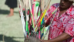 Seorang pria menunjukkan lembing yang menancap pada kelapa saat kompetisi panjat pohon kelapa di Papeete, Polinesia (15/7). Kompetisi ini diikuti peserta hingga kepulauan di Samudera Pasifik, Hawaii dan Kepulauan Samoa. (AFP Photo/Gregory Boissy)